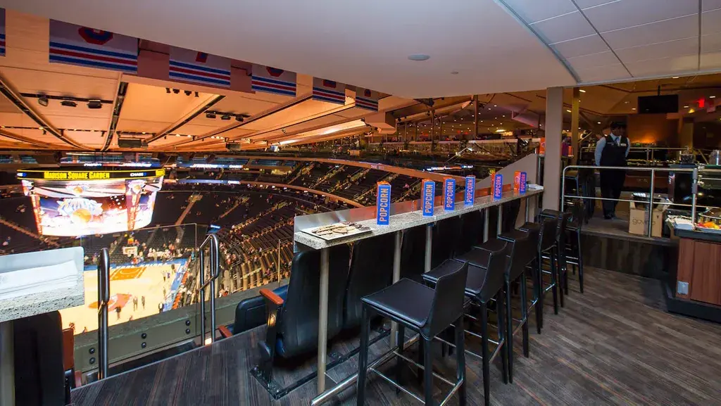 Private sports suite with counter seating overlooking a basketball game at Madison Square Garden