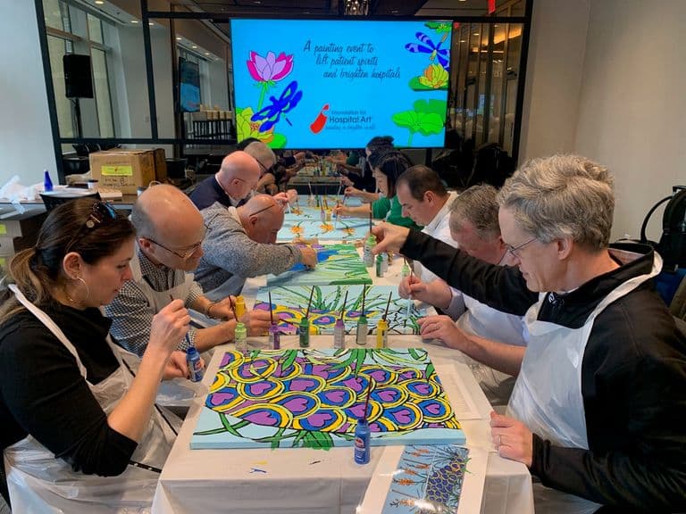 Group of coworkers painting vibrant murals side by side during a team volunteer event.