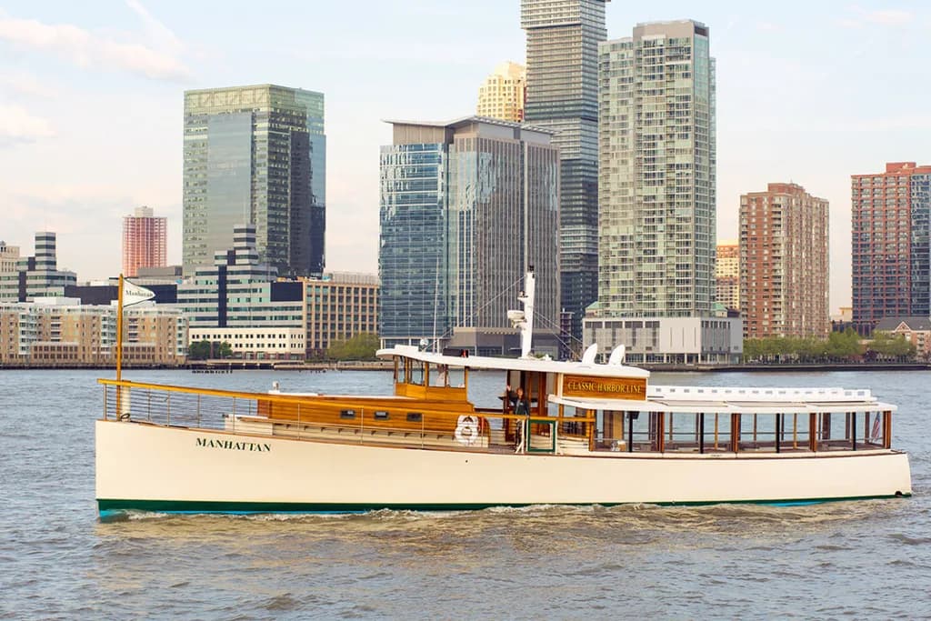 a close up of a classic yacht on the water with the city in the background
