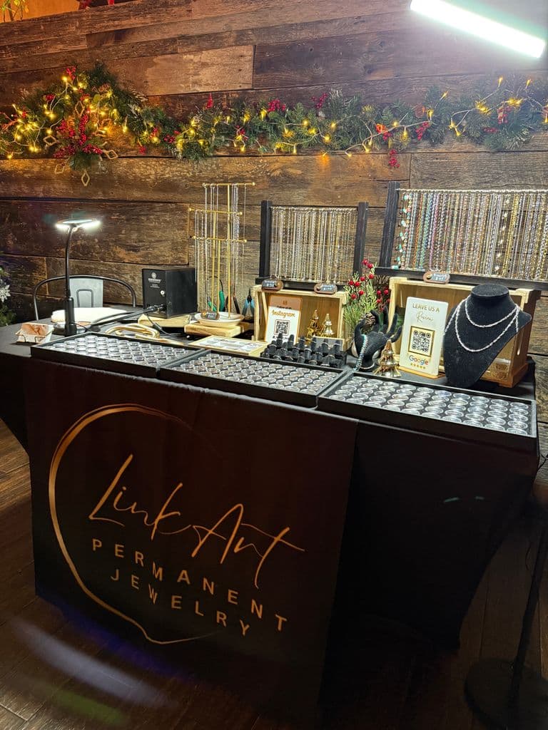 Permanent jewelry pop-up booth with gold chains display and branded table setup at event