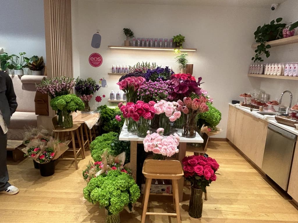 A cozy floral bar filled with fresh pink, green, and purple flower arrangements on stools and tables.