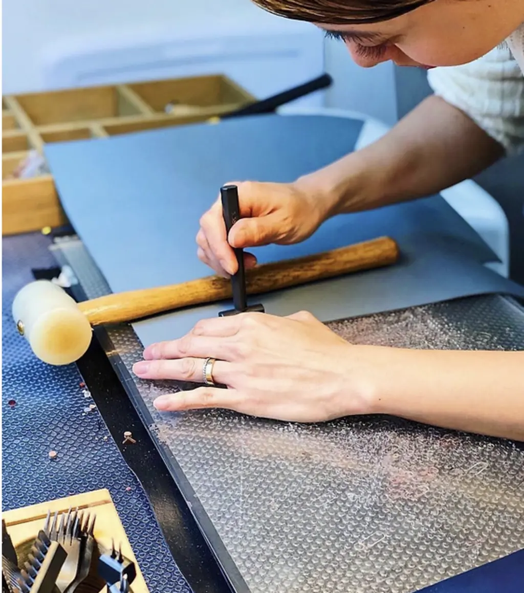 a person with a stamp and hammer making a passport holder