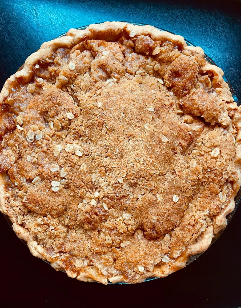 A close-up of a crumbly, golden pie with an oat topping, freshly baked and ready to be served.