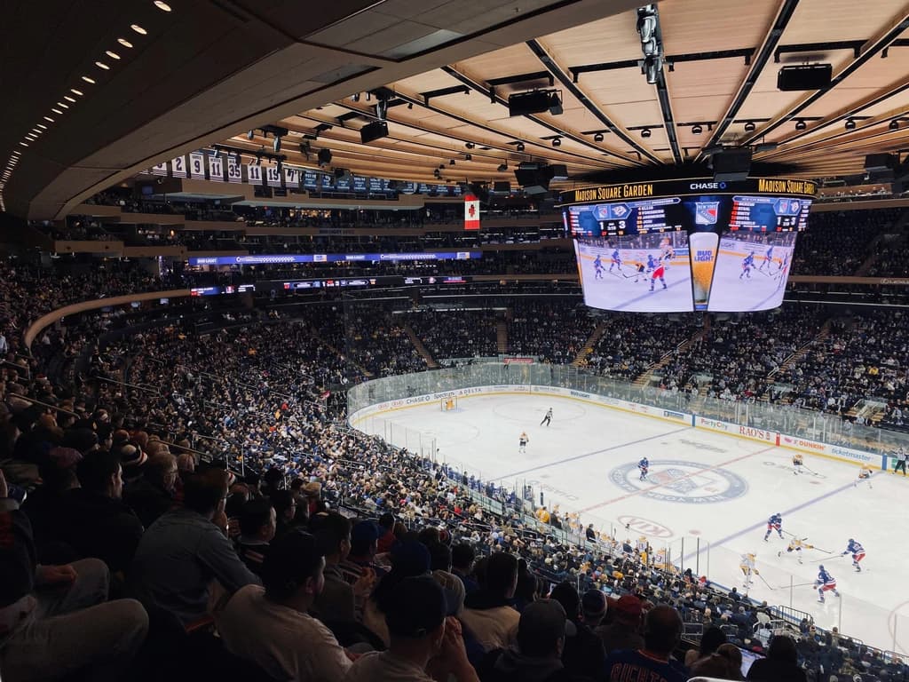 Crowd watching a New York Rangers hockey game at Madison Square Garden, with a view of the ice rink