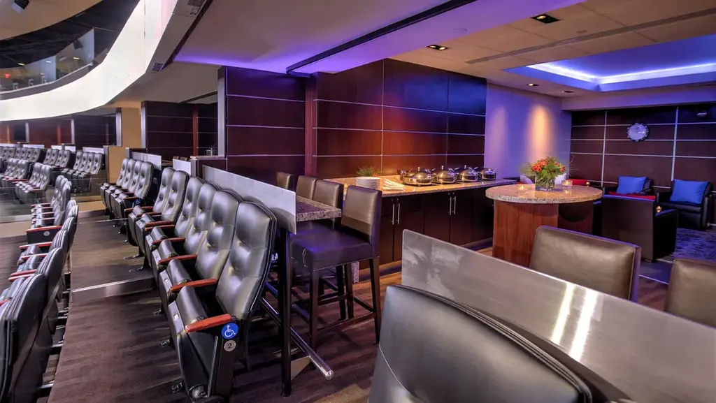 Spacious private suite at Madison Square Garden, featuring a view of the rink, leather seating, and a private catering area.
