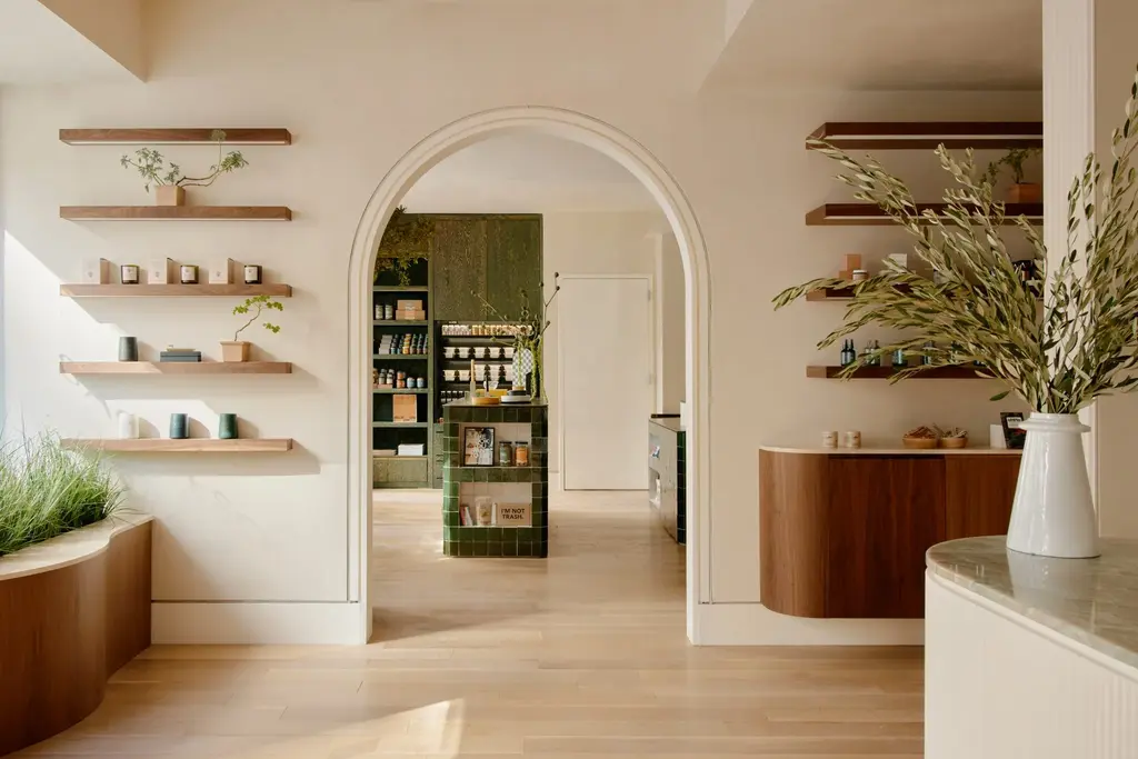an open room with shelves and a counter with plants, candles, and frangrances on the shelves